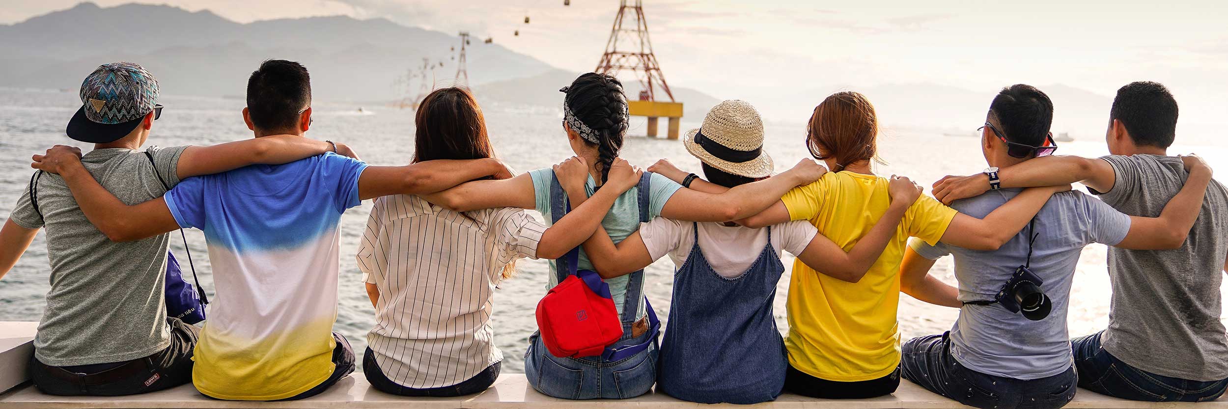 A group of people linking arms in front of a body of water
